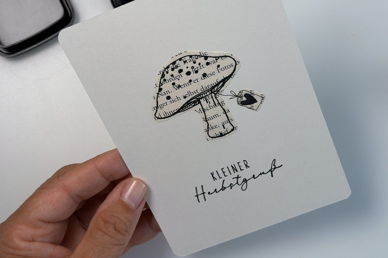 Selbstgemachte Herbstkarte mit Fliegenpilz aus einer alten Buchseite und dem Schriftzug Kleiner Herbstgruß